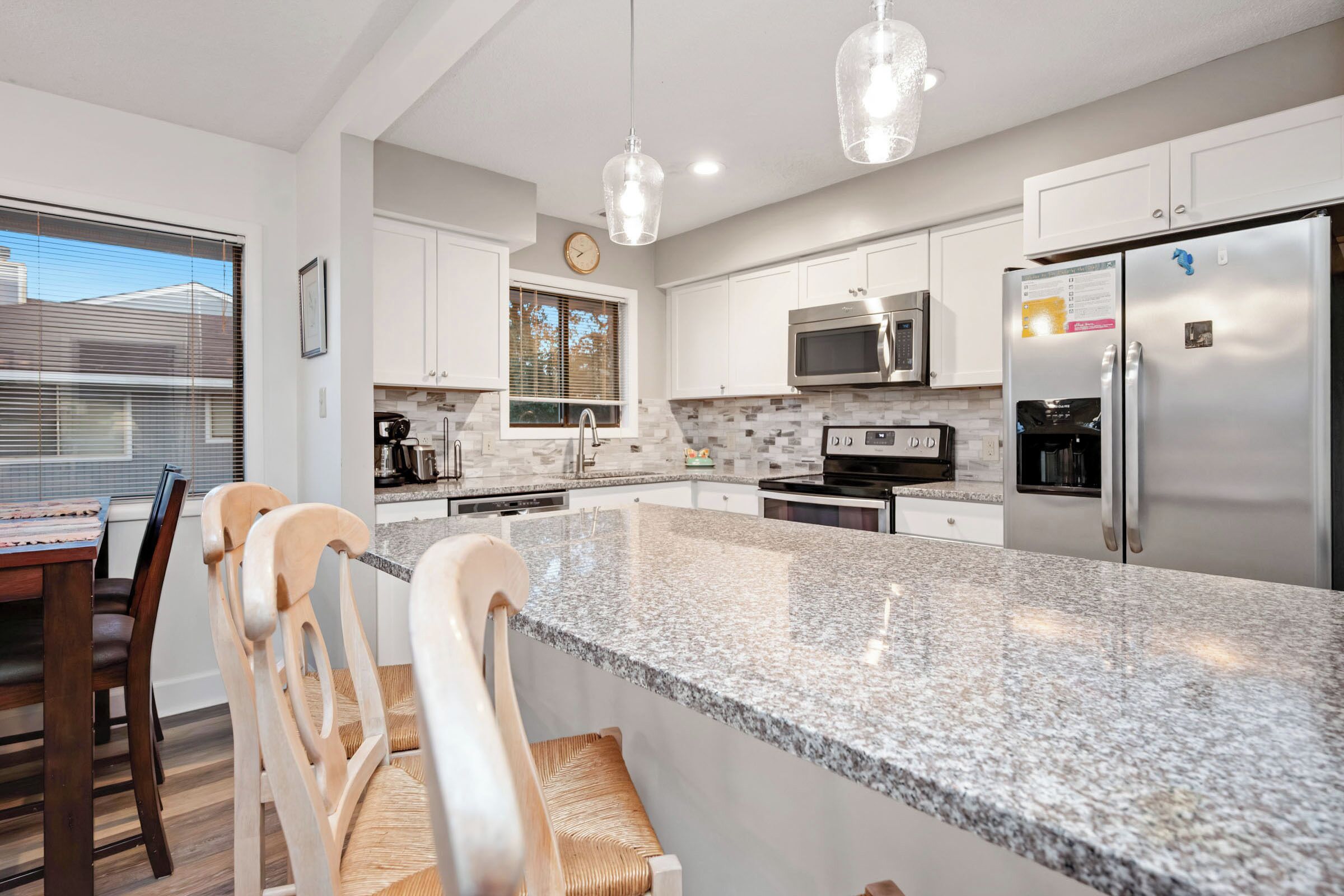 A modern kitchen with granite countertops, stainless steel appliances, and pendant lighting.