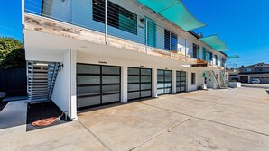 A modern two-story building with large garage doors, a covered outdoor area, and a staircase leading to the upper floor. - Oceanviews, Steps to the Sand, Short Walk to the Village! A/C (Carlsbad)