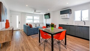 A modern kitchen with a dining area, a sofa, and a TV mounted on the wall. - Oceanviews, Steps to the Sand, Short Walk to the Village! A/C (Carlsbad)