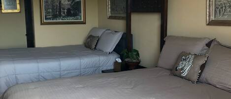 A hotel room with two beds, a wooden headboard, and framed artwork on the walls.