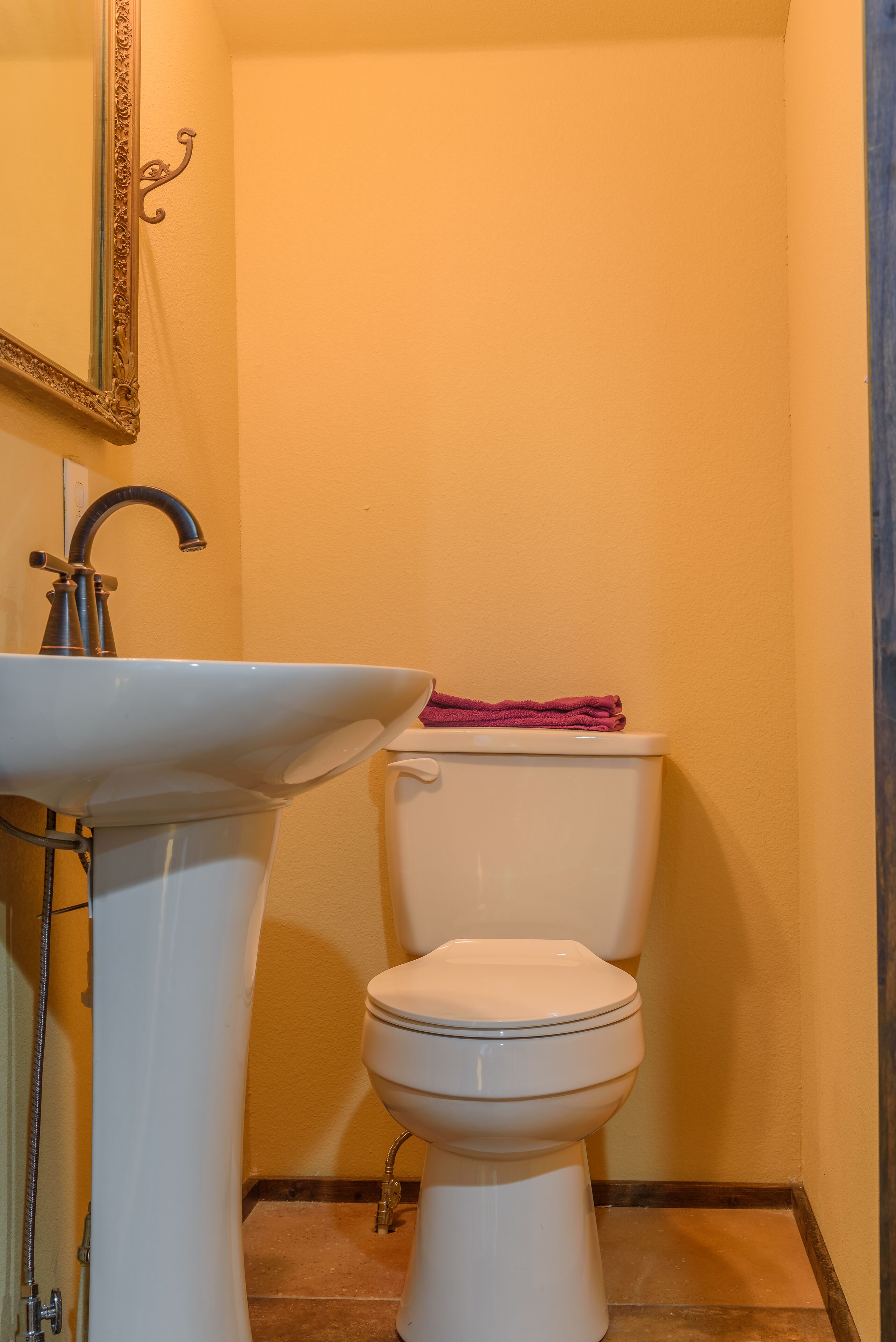 A bathroom with a white sink, toilet, and a mirror with an ornate frame.