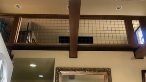 Una habitación con techo alto, vigas de madera a la vista, pared de azulejos y un espejo grande con marco decorativo.