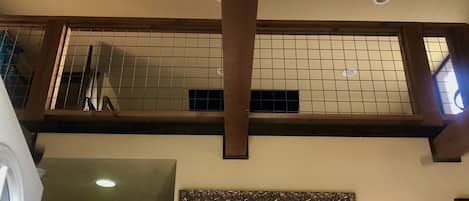 Una habitación con techo alto, vigas de madera a la vista, pared de azulejos y un espejo grande con marco decorativo.