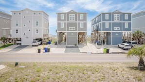 Un hilera de casas adosadas de tres pisos, con una entrada central, zona de estacionamiento y contenedores de basura visibles.