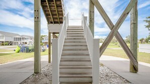 Una escalera de madera que lleva a un espacio cubierto con vistas a casas al fondo.