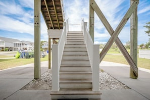 Eine Holztreppe führt zu einem überdachten Bereich mit Blick auf Häuser im Hintergrund.