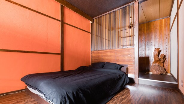 A modern bedroom with a wooden bed, a sliding wooden door, and a wooden floor.
