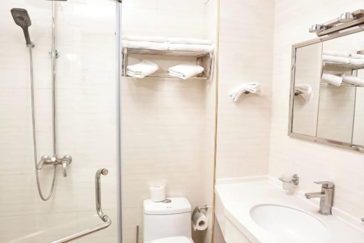 A modern bathroom with a glass shower enclosure, a toilet, a sink, and a towel rack.