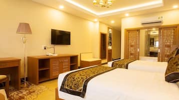 Una habitación de hotel con dos camas, televisión, escritorio, lámpara y armario.