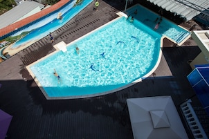 Uma piscina com deck de madeira e um mural na parede vizinha.
