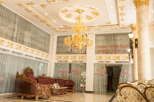Um hall luxuoso com mobiliário requintado, um imponente candelabro e detalhes decorativos no teto.