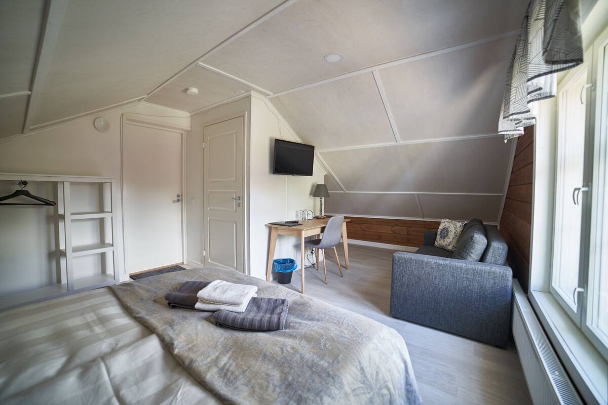 Een slaapkamer met een bed, bureau, stoel, bank en televisie.