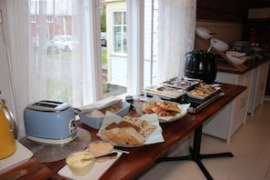 A breakfast buffet with various food items, a toaster, and a coffee maker on a wooden table.