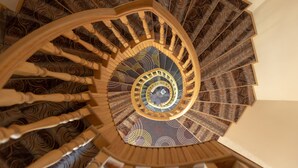 A spiral staircase with ornate wood railings and a patterned carpet. - STAR Hotel (Baku)