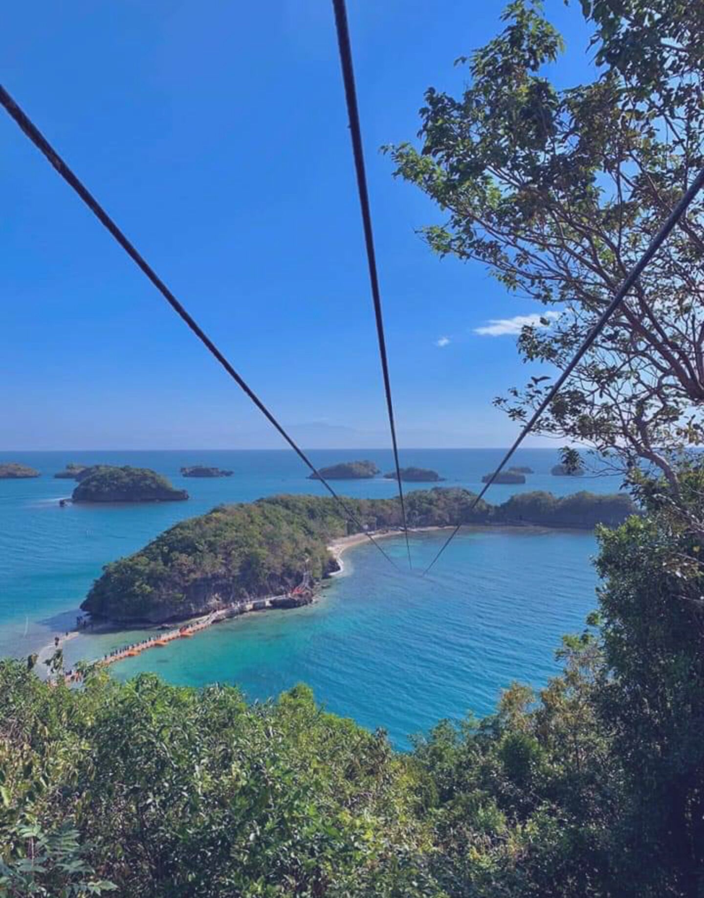 A scenic view of a coastal area with clear blue waters, lush greenery, and several small islands.