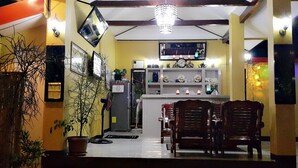 A compact kitchen with a dining area, featuring a chandelier, a refrigerator, and a small island with a sink.