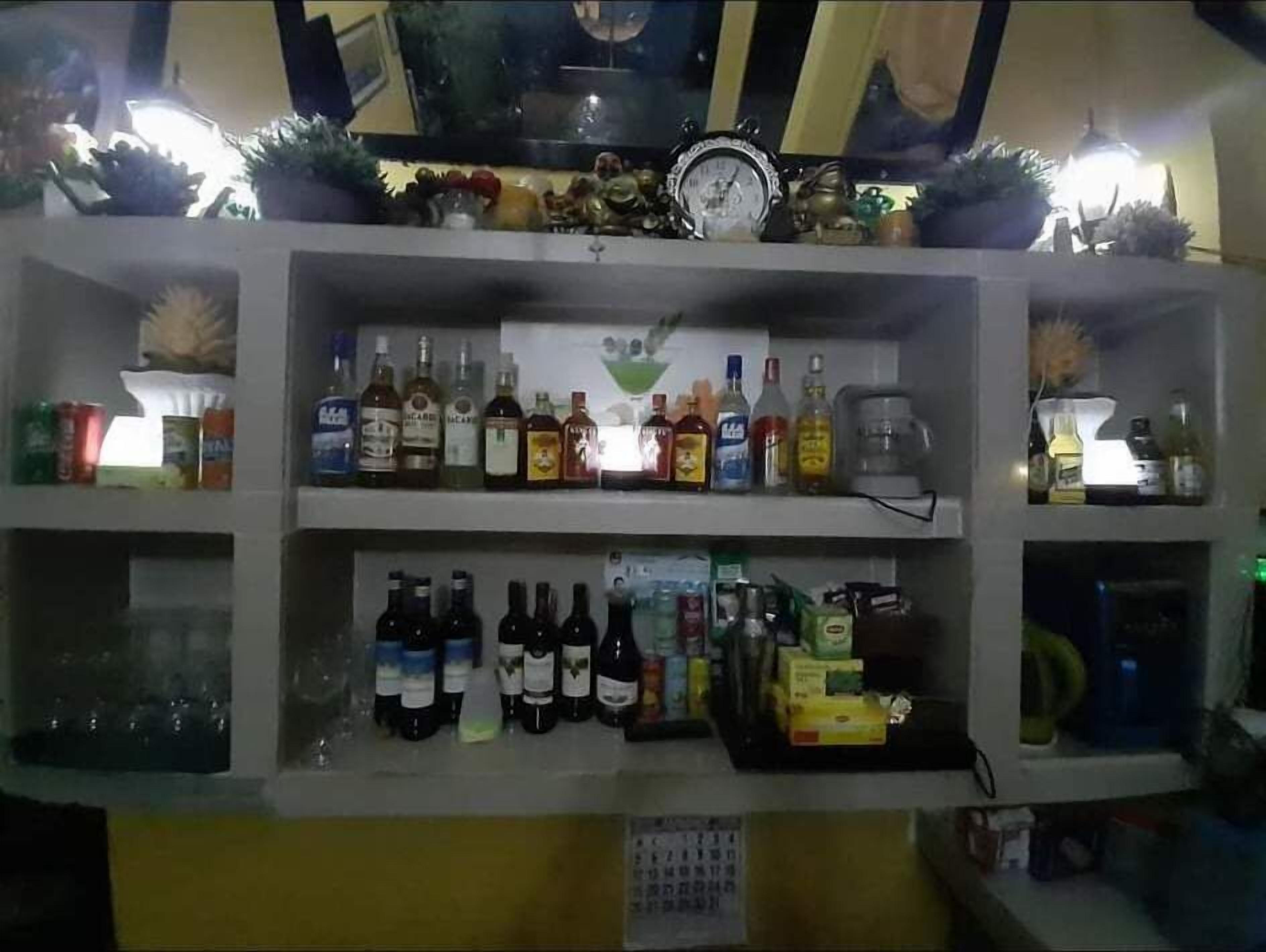 Un'area bar con scaffali pieni di bottiglie di liquore e un orologio appeso al muro.