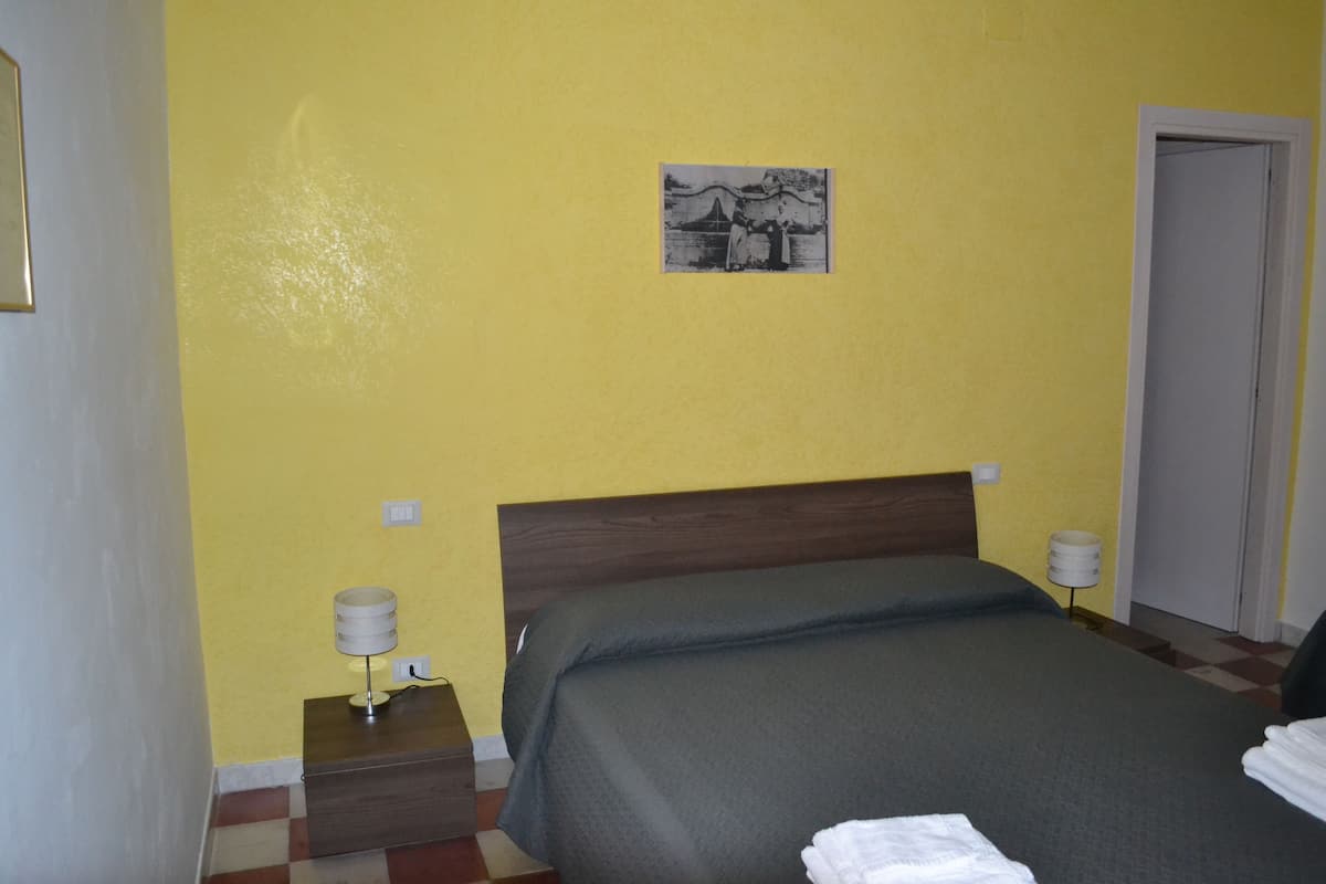 A hotel room with a bed, a nightstand, a lamp, and a painting on the wall.