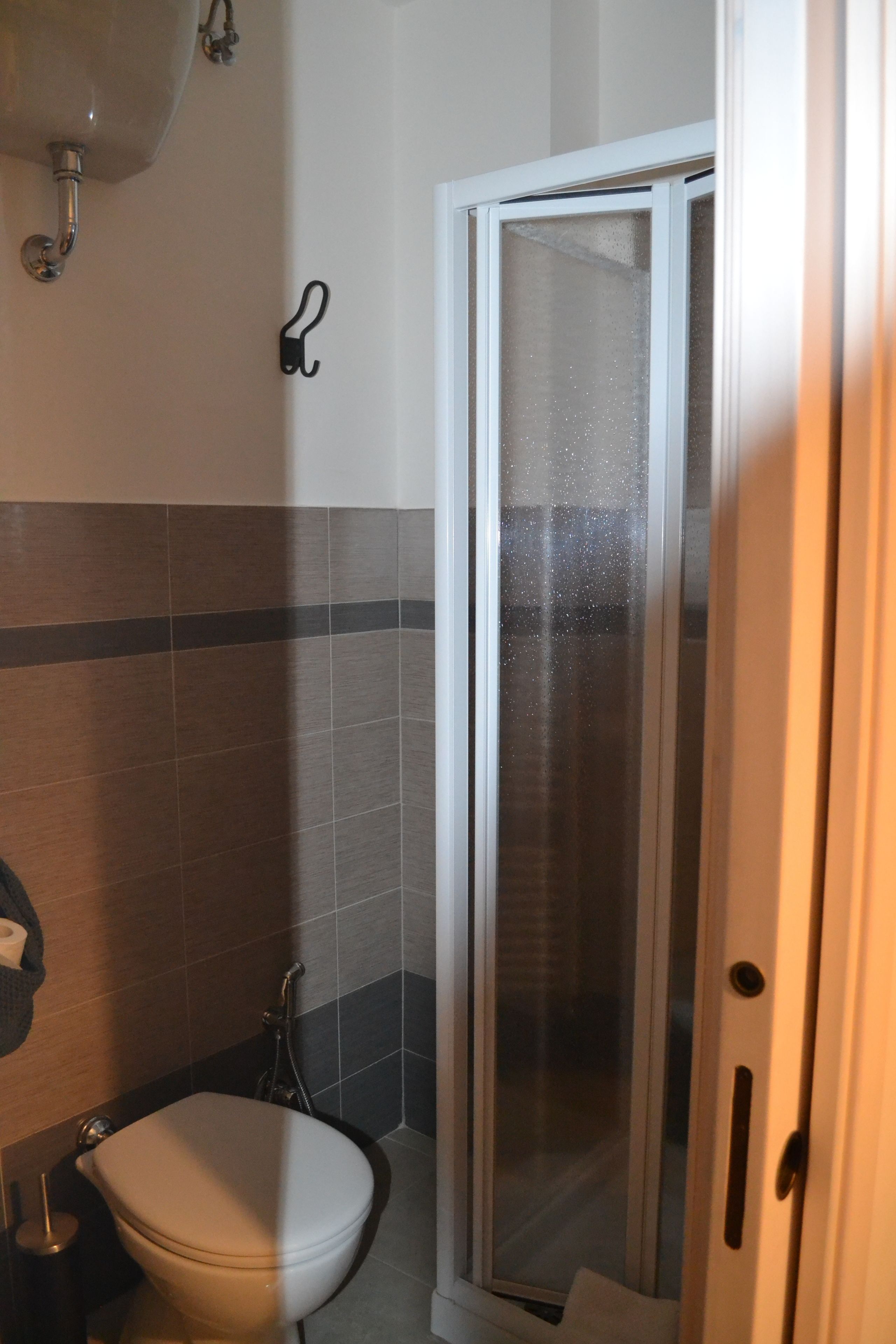 A bathroom with a toilet, a shower with a glass door, and a towel rack.