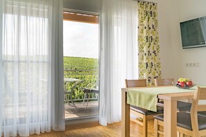 Une pièce avec une table en bois, des chaises, une nappe verte et un panier de fruits.