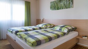 Ein Doppelbett mit kariertem Bettbezug und Kissen, ein Nachttisch mit einem Buch und ein Bild an der Wand.