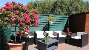 Un patio al aire libre con muebles de mimbre, una planta en maceta y una valla de madera.