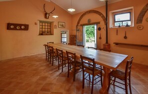 A dining area with a long wooden table and chairs, a mounted deer skull, and a rustic archway.