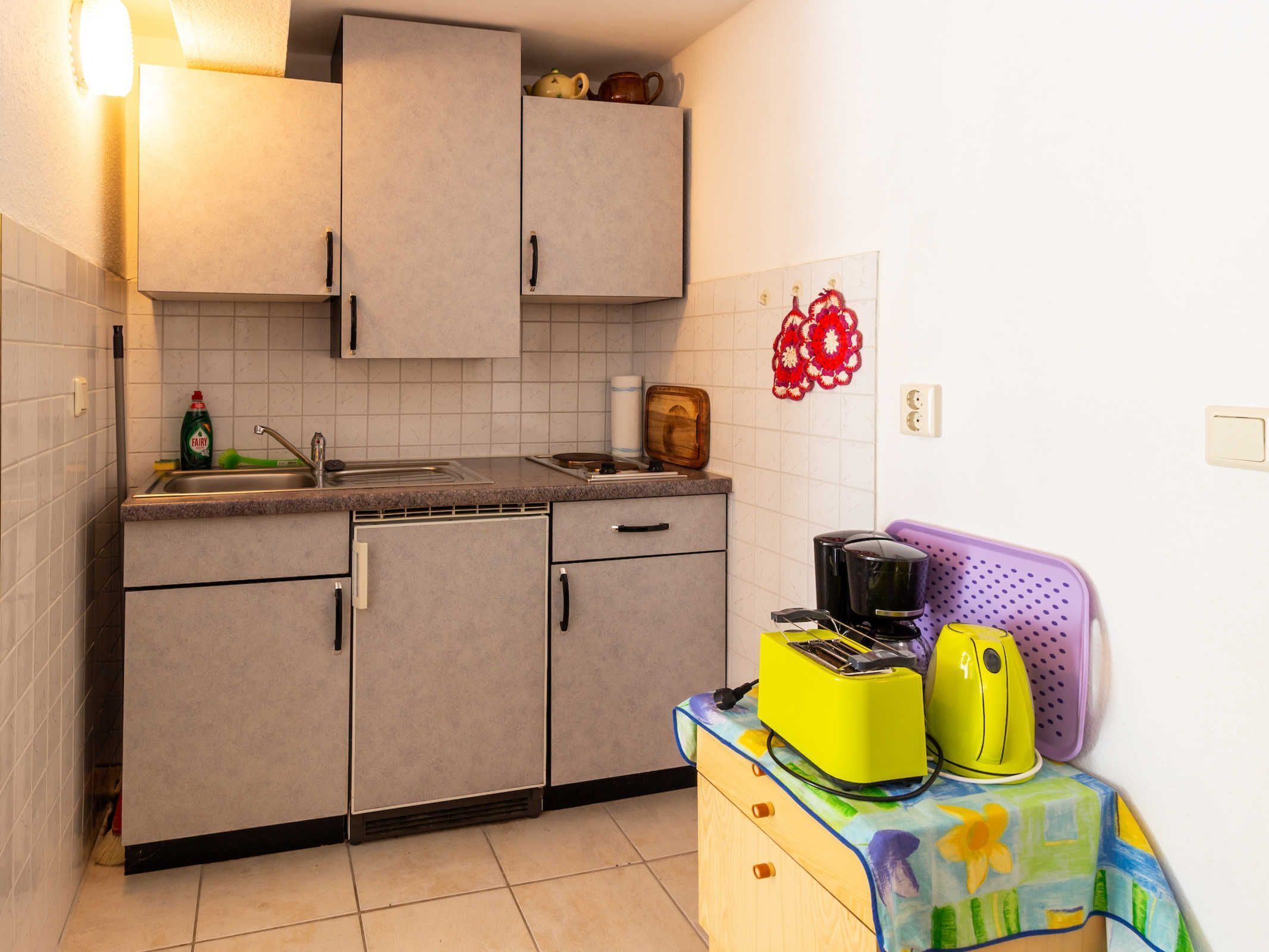 A kitchen with grey cabinets, a sink, and a toaster on a colorful table.