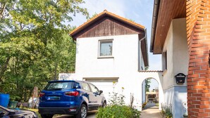 A two-story house with a garage, a driveway, and a garden with potted plants. - Holiday apartment - FH VIL 0062 (Patzig)