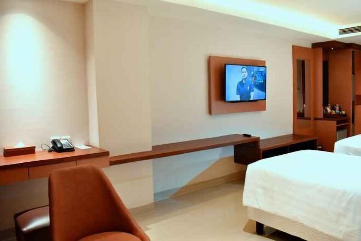 Une chambre d’hôtel comprenant un lit, un bureau avec un téléphone, un téléviseur fixé au mur et une chaise.