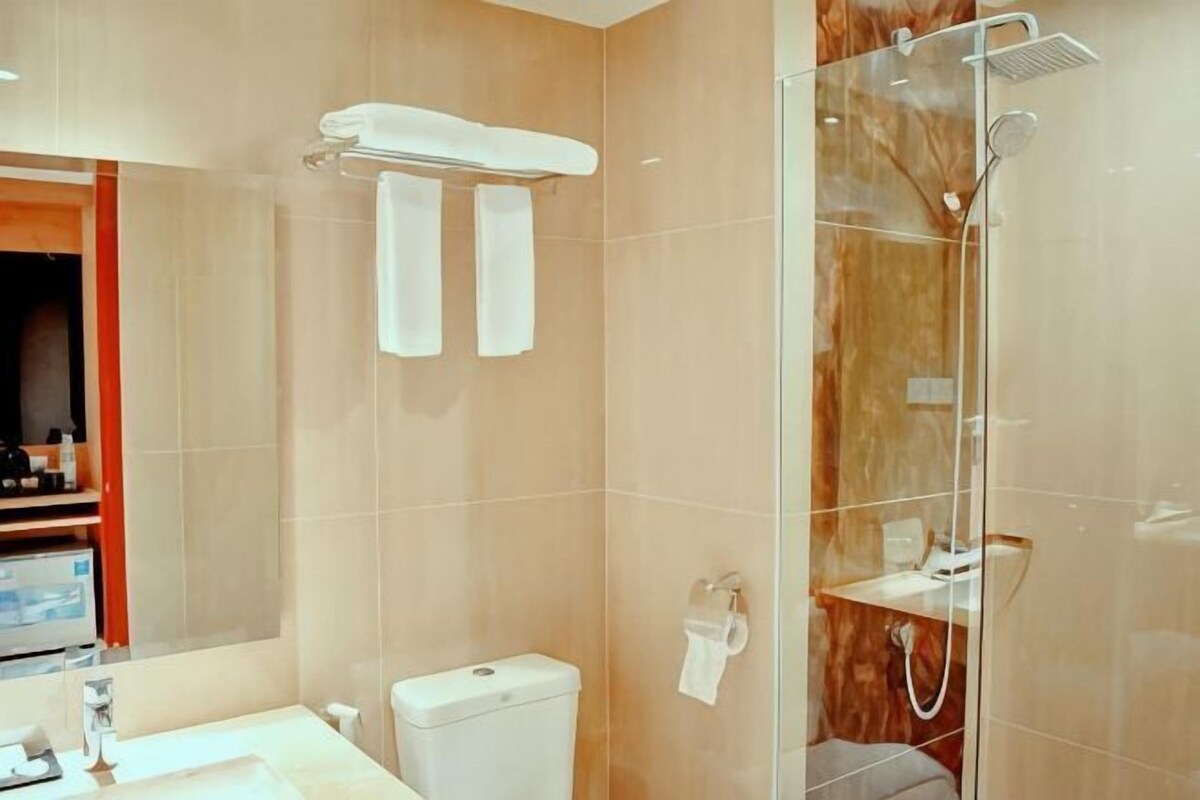 Une salle de bain équipée de toilettes, d’un lavabo et d’une douche à parois de verre.