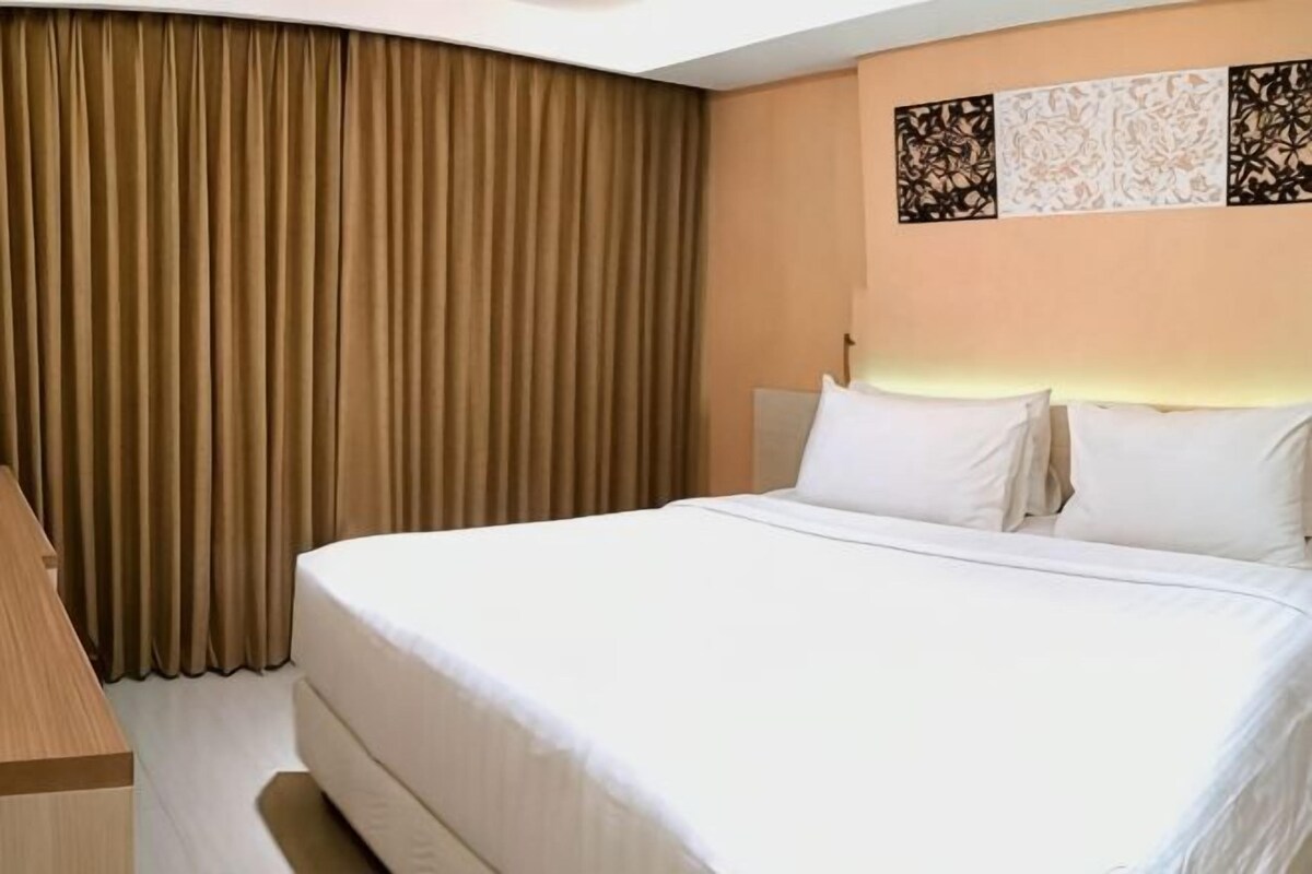 Une chambre d’hôtel avec un grand lit, des rideaux et des œuvres d’art murales.
