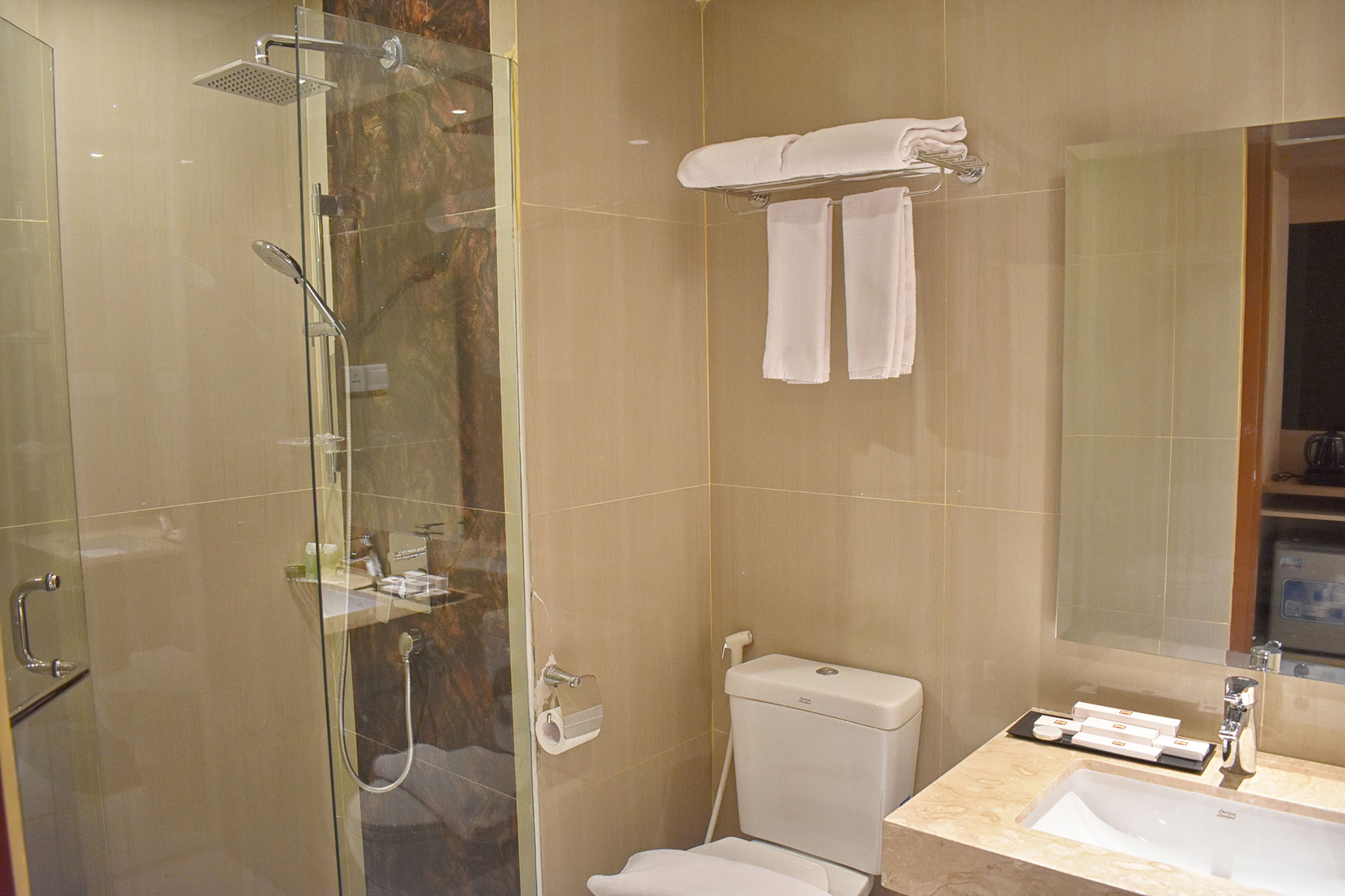 Une salle de bain moderne avec une douche à parois de verre, des toilettes et un lavabo avec un miroir au-dessus.