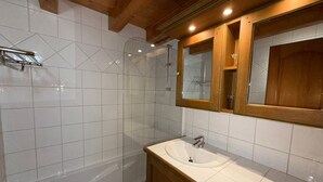 A bathroom with a glass-enclosed shower, a white sink, and wooden cabinets. - 3-room Apartment Les Saisies, 6 pers, balcony, 2 baths, ski locker (Les Saisies)