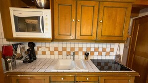 A kitchen with wooden cabinets, a white microwave, and a tiled backsplash. - 3-room Apartment Les Saisies, 6 pers, balcony, 2 baths, ski locker (Les Saisies)