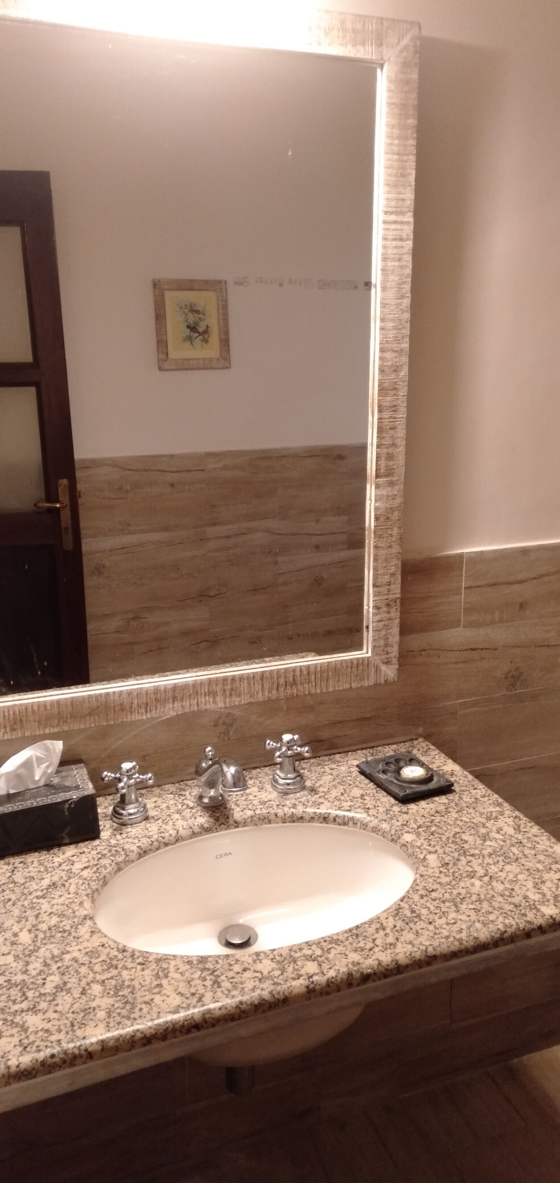 Un bagno con un piano in granito, un lavandino bianco e uno specchio grande.