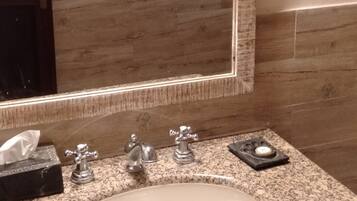 Un bagno con un piano in granito, un lavandino bianco e uno specchio grande.