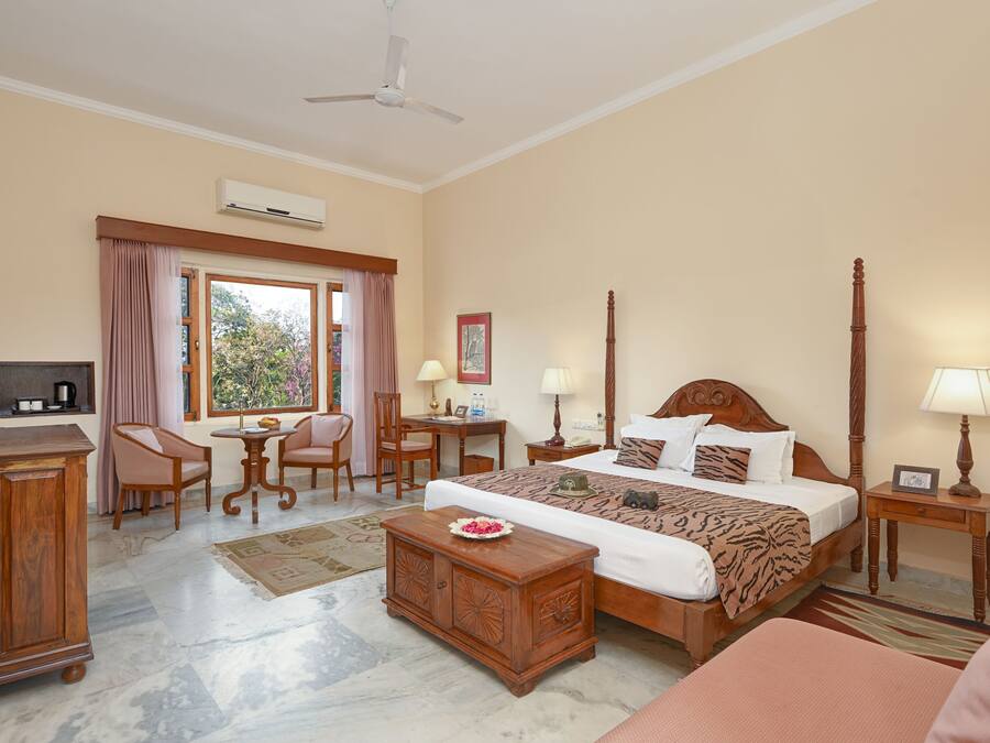 A hotel room with a bed, desk, chairs, and a television.
