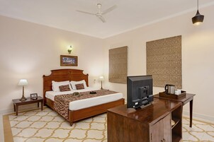 Habitación de hotel con una cama de madera, un escritorio con televisor y paredes con estampado.