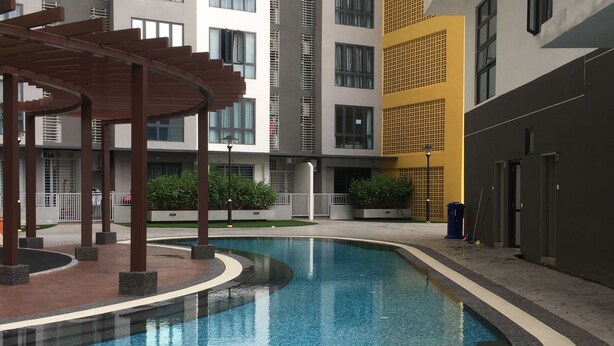 A swimming pool with a curved edge, surrounded by a paved walkway. In the background, there are multi-story residential buildings with balconies and windows. - Silk Sky Residence (Seri Kembangan)