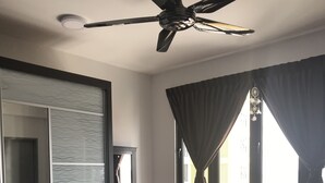 A bedroom with a bed, a ceiling fan, a window with curtains, and a dresser. - Silk Sky Residence (Seri Kembangan)