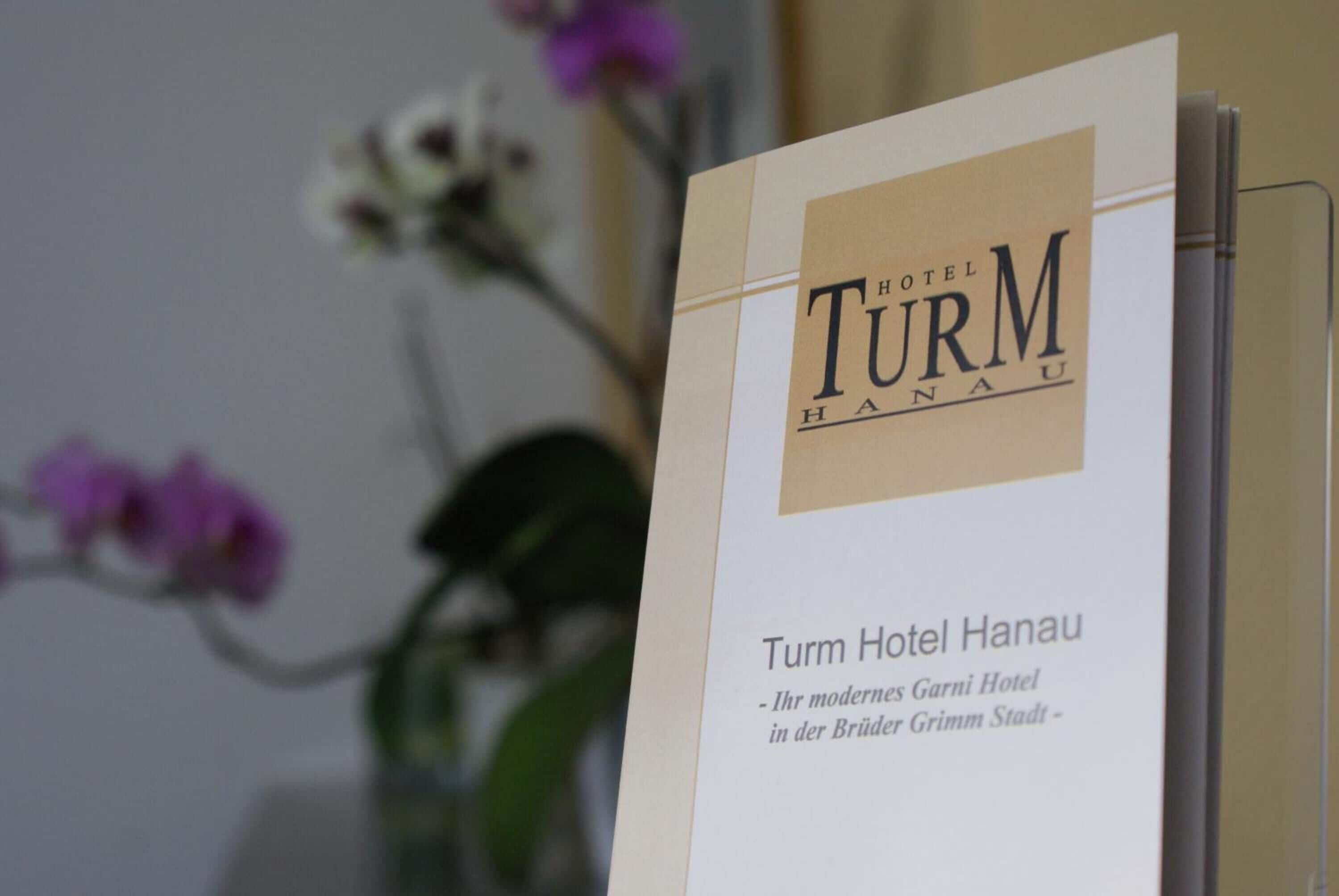Eine Broschüre für das Turm Hotel Hanau, die seinen modernen Standort als Garni Hotel in der Stadt der Brüder Grimm hervorhebt.