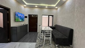 A modern room with a dark sofa, a small table, and a TV mounted on the wall. - VM Hostel (Ganja)
