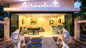 A modern hotel entrance with a reception desk, seating area, and two lion statues. - Achawalai By PP (Pattaya)