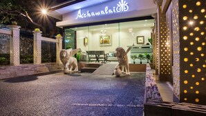 A hotel entrance with a lion statue, a sign reading "Achawali", and a well-lit interior visible through the glass doors. - Achawalai By PP (Pattaya)