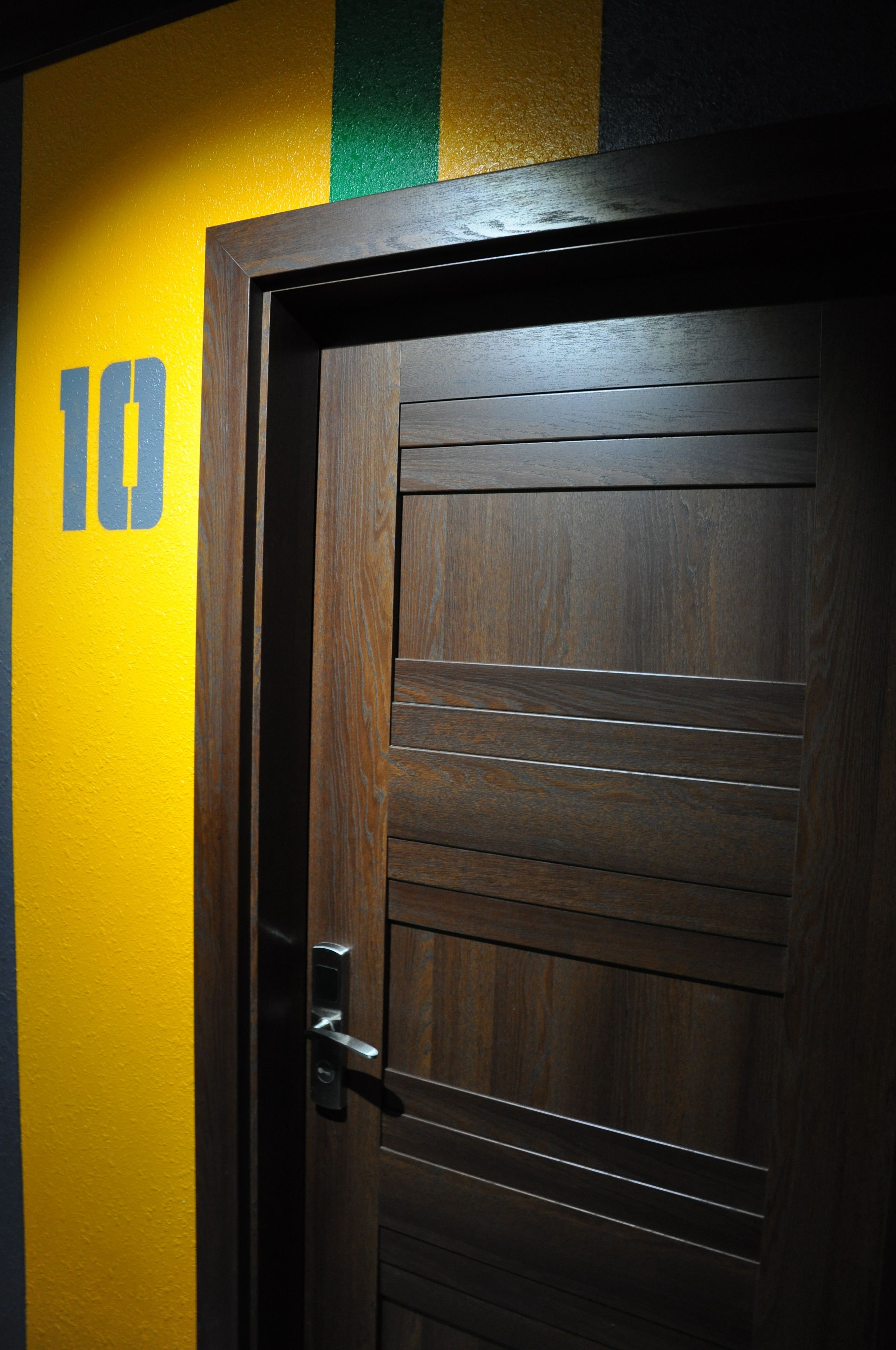 A wooden door with a metal handle and a number "10" on the wall beside it.