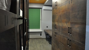 A hotel room with a green view, wooden cabinets, and a bench. - Full House Capsule Hostel (Rivne)
