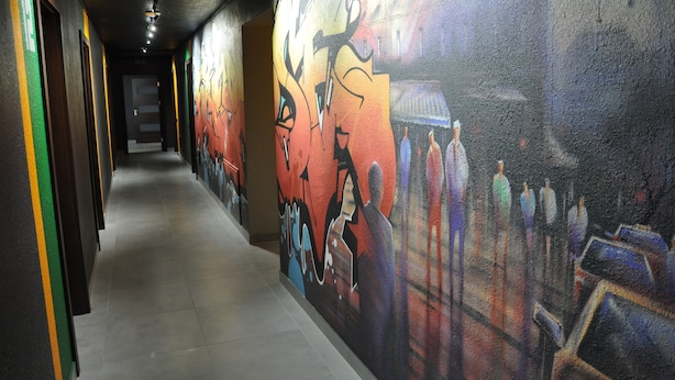 A hallway with a colorful mural on the walls, a tiled floor, and doors on the left. - Full House Capsule Hostel (Rivne)