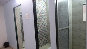 A bathroom with a shower, tiled walls, and a mirror. - Sunshine Hostels (Mumbai)