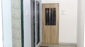 A hallway with a wooden door, a glass door, and a marble wall. - Sunshine Hostels (Mumbai)